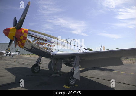 North American P-51 Mustang fighter Sweet Mary Lou in chrome, yellow, and red sits on the tarmac in the sun Stock Photo