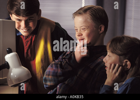 Happy Boy with Down Syndrome and Friends Playing on Home Computer Stock Photo