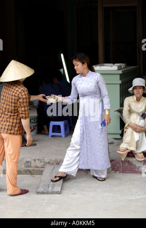 Woman in a traditional hat delivers soup to a woman in traditional clothes.   Saigon (HCMC) Vietnam Stock Photo