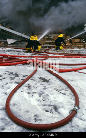 A fire fighter uses a water hose to douse a fire Stock Photo - Alamy