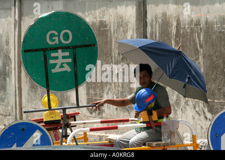 Shaded construction worker changes traffic signs, Hong Kong Stock Photo