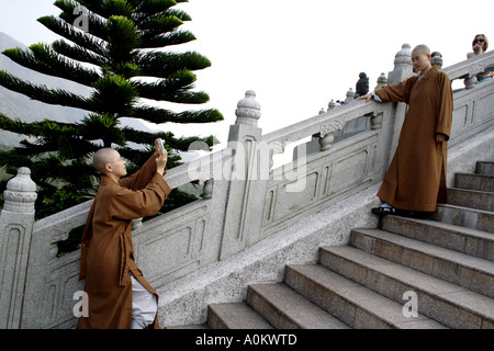 A nun takes a picture of another nun in front of the Tian Tan Buddha, Lantau Island, Hong Kong Stock Photo