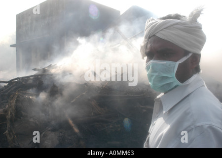 man wearing mask at funeral pyre burning dead after Tsunami earthquake Nagapattinum Velankanni Tamil Nadu India Stock Photo