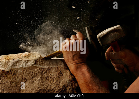 A stonemason works with hammer and cold chisel in studio light Stock Photo