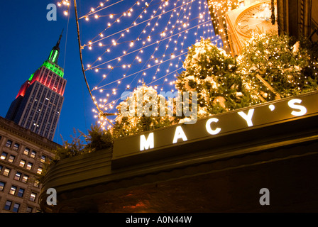 Macy s department store sign during Christmas season with view to the Empire State Building Midtown Manhattan New York USA Stock Photo