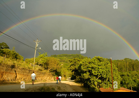 People walking under rainbow in the Tilaran Mountain Range close to Monteverde, Puntarenas Province, Costa Rica, Central America Stock Photo