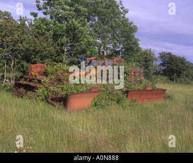 Eire Co Galway Two abandoned rusty caterpillar bulldozers in roadside field Stock Photo