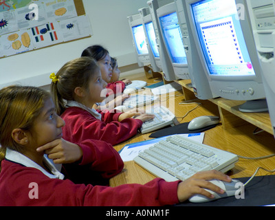 Junior multicultural school children girls 7-9 years in their modern school computer class looking at their study computer screens. Stock Photo
