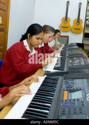 MUSIC CLASS KEYBOARDS Teenage students wearing earphones practice & compose playing scales together on electronic pianos in school music classroom Stock Photo