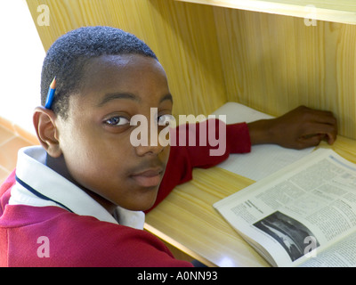 Schoolboy Teenage African Afro black Teenage 14-16 years boy pupil in uniform studying in school library booth Stock Photo