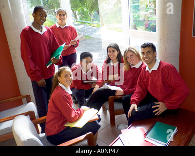 School group of happy attractive multicultural teenage students in school uniform together in sunny modern school senior common room Stock Photo
