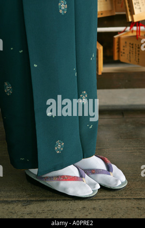 Closeup of a Japanese woman wearing a traditional dark green silk kimono with white tabby socks and ancient sandals visits Kyoto Stock Photo