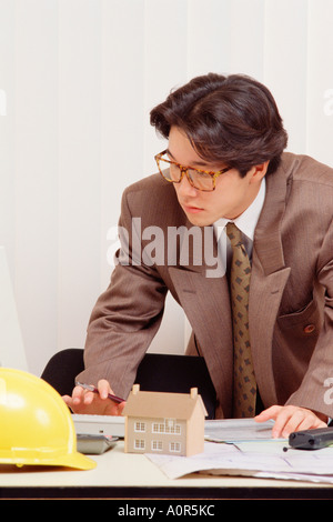 Young man in suit working while standing at his desk. Stock Photo