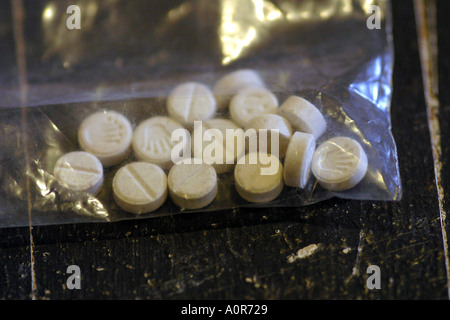 Pills E Ecstasy tablets in a plastic bag on a black dirty table Stock Photo