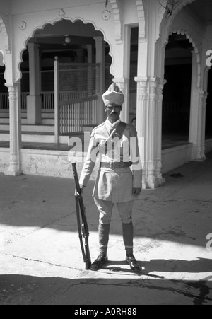 Portrait man stand pose outdoor street tradition colonial imperial guard rifle turban hat Mysore Karnataka India South Asia Stock Photo