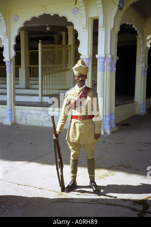 Portrait man stand pose outdoor street tradition colonial imperial guard rifle turban hat Mysore Karnataka India South Asia Stock Photo