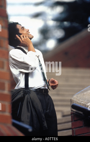 Asian American businessman Laughing and talking on mobile phone outdoors Stock Photo