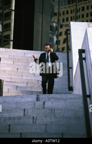 Businessman rushing through the Wall Street area of New York While talking on his mobile phone Stock Photo