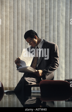 Relaxed and thoughtful Caucasian executive alone in a conference room reviewing a report Stock Photo