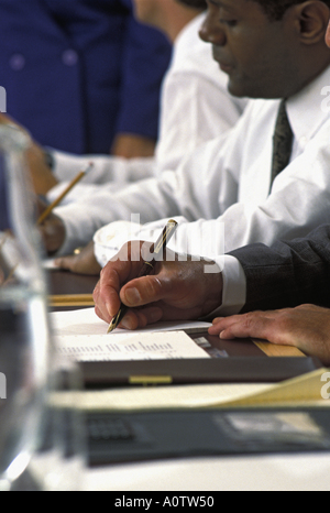 Closeup of an African American executive's hand making notes  while participating in a business meeting Stock Photo