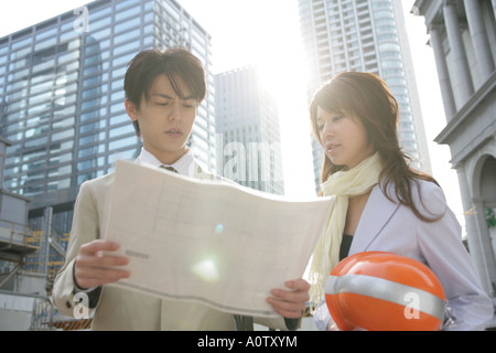 Low angle view of a male and a female architect looking at a blueprint Stock Photo