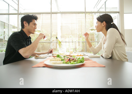 Side profile of a young couple sitting at the dining table and drinking white wine Stock Photo