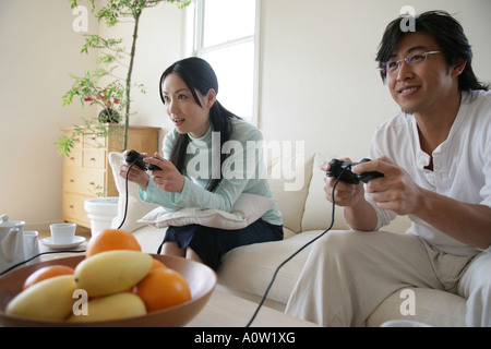 Young couple sitting on a couch and playing video games Stock Photo