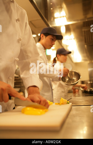 Two male chefs and a female chef preparing food in the kitchen Stock Photo