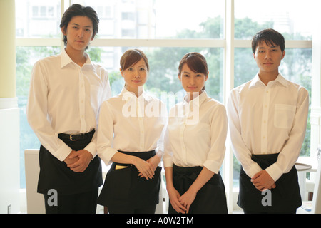 Portrait of two waiters and two waitresses standing in a restaurant Stock Photo