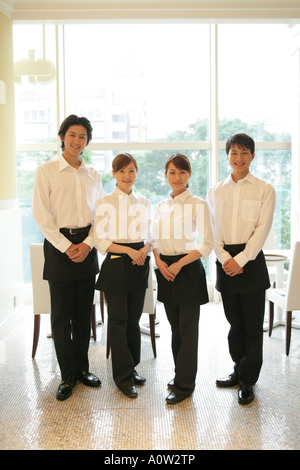 Portrait of two waiters and two waitresses standing in a restaurant Stock Photo