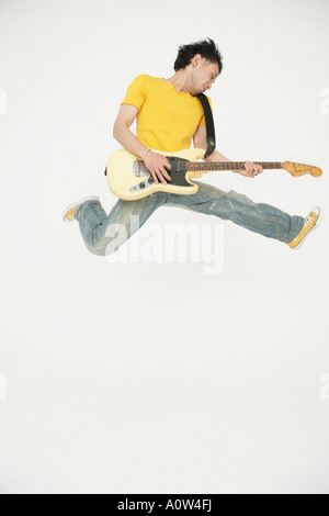Young man playing an electric guitar and jumping Stock Photo