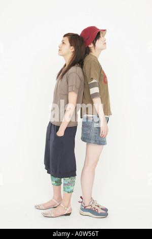 Two young women standing back to back, white background Stock Photo - Alamy