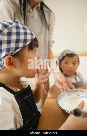 Mid adult woman and her two daughters making a cake Stock Photo