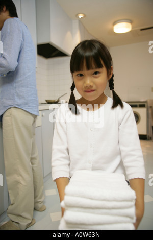Portrait of a girl carrying a stack of folded towels Stock Photo - Alamy