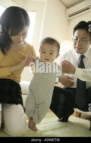 Mid adult couple helping their baby boy stand Stock Photo