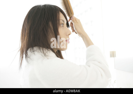 Side profile of a young woman brushing her hair Stock Photo