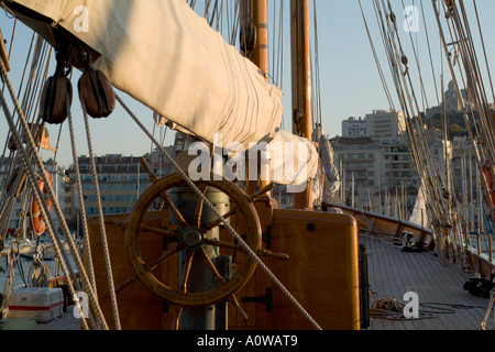 Steering wheel of an old-fashioned sailing ship with Notre Dame de la Garde visible in background, Vieux-Port, Marseille, France Stock Photo