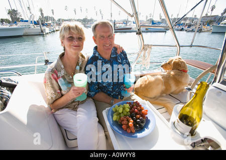 Retired couple enjoy wine and snacks on their sailboat Stock Photo