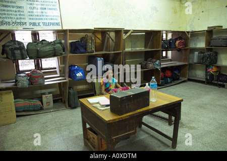 India Rajasthan Jodhpur railways Jodhpur train station Left luggage room view with luggage on shelves and young woman sitting in Stock Photo