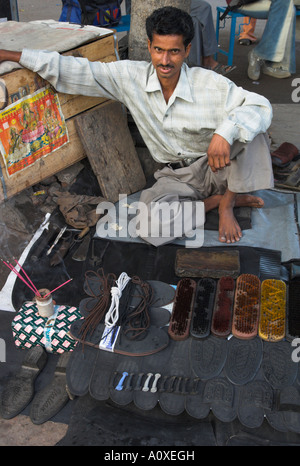 India Rajasthan Udaipur street shoe maker sitting on the floor at his very orderly shoe fixing stall Stock Photo