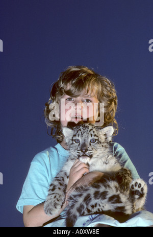 7 year old Megan Whittaker with hand raised 8 week old snow leopard cub born at Port Lympne Wild Animal Park, Kent, UK Stock Photo