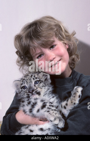 7 year old Megan Whittaker with hand raised 8 week old snow leopard cub born at Port Lympne Wild Animal Park, Kent, UK Stock Photo