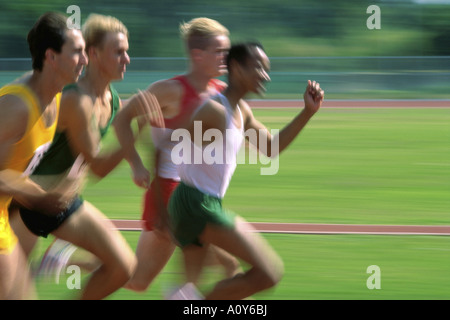 Side profile of four athletes running on a running track in a race Stock Photo