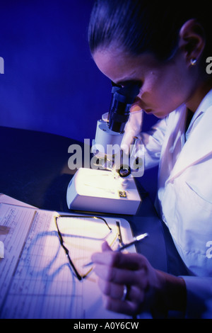 Side profile of a female researcher looking through a microscope Stock ...