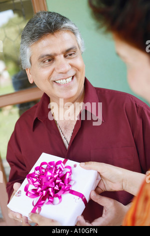 Close-up of a mature woman taking a birthday present from a mature man Stock Photo