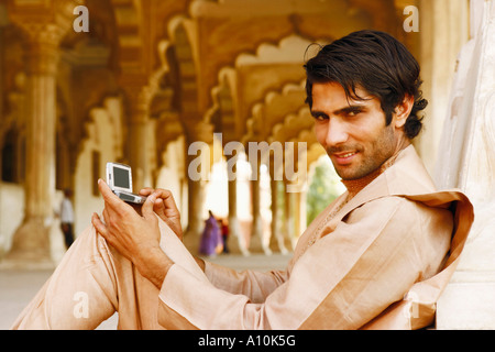 Portrait of a young man holding a hand-held device, Agra Fort, Agra, Uttar Pradesh, India Stock Photo