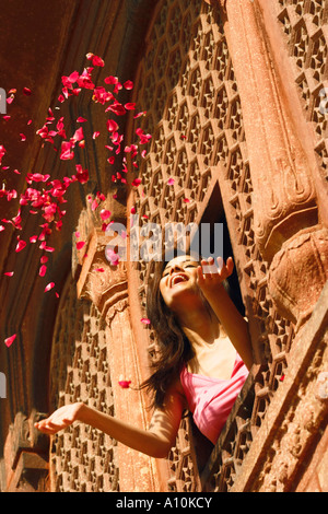 Low angle view of a young woman throwing rose petal from a window, Agra Fort, Agra, Uttar Pradesh, India Stock Photo