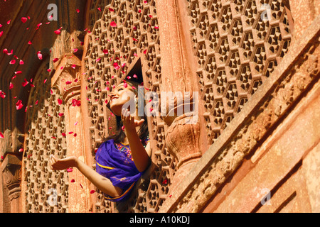 Low angle view of a young woman throwing rose petal from a window, Agra Fort, Agra, Uttar Pradesh, India Stock Photo