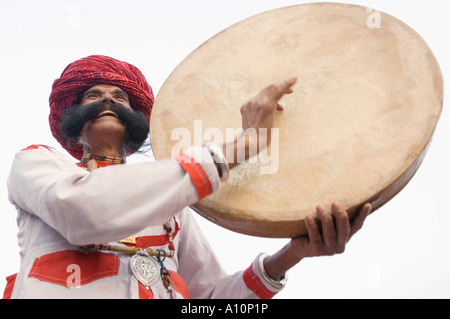 Low angle view of a mature man playing a drum, Elephant Festival, Jaipur, Rajasthan, India Stock Photo