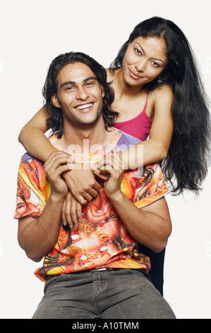 Mid adult man embracing a young woman sitting on the bonnet of a jeep ...